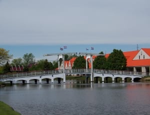white traditional bridge near orange roofed house thumbnail