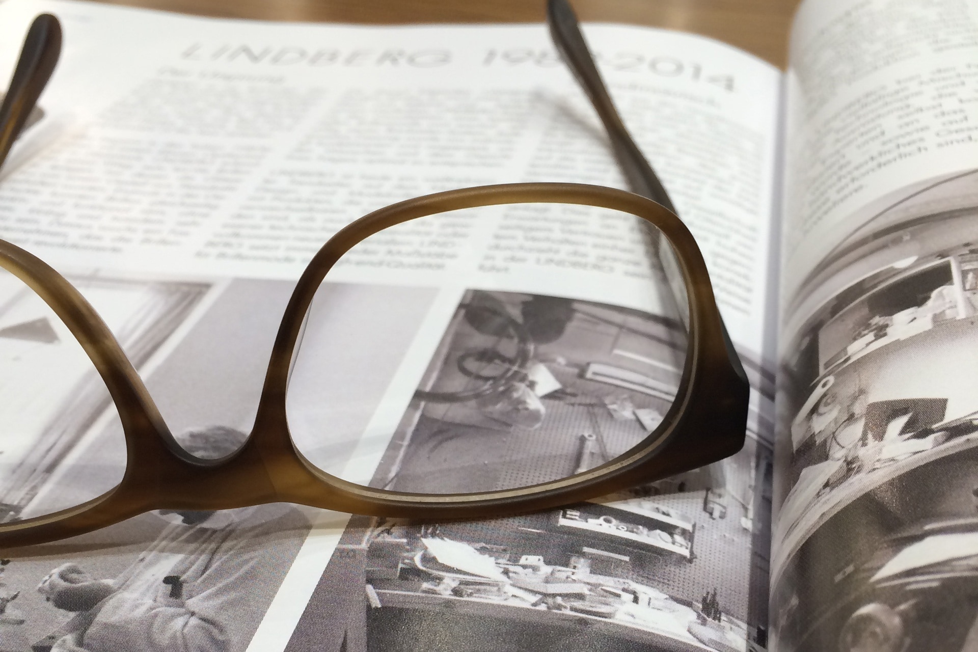 brown framed eyeglasses on top of grayscale photography magazine