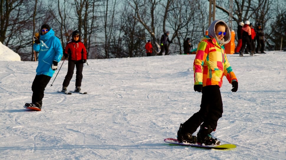 person in yellow and red hoodie and black pants snowboarding preview