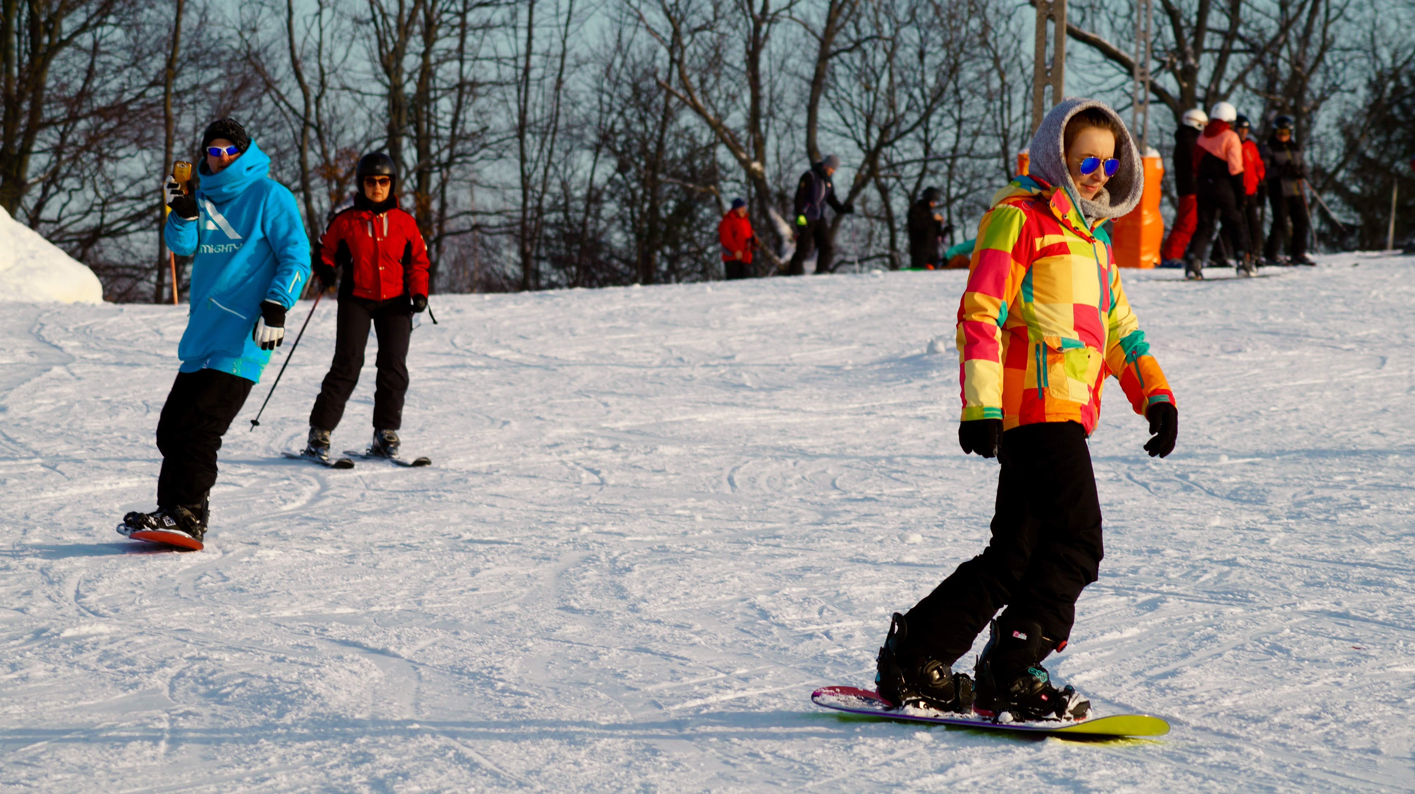 person in yellow and red hoodie and black pants snowboarding