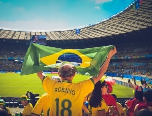 man wearing yellow robinho 18 jersey shirt holding up banner on football stadium thumbnail