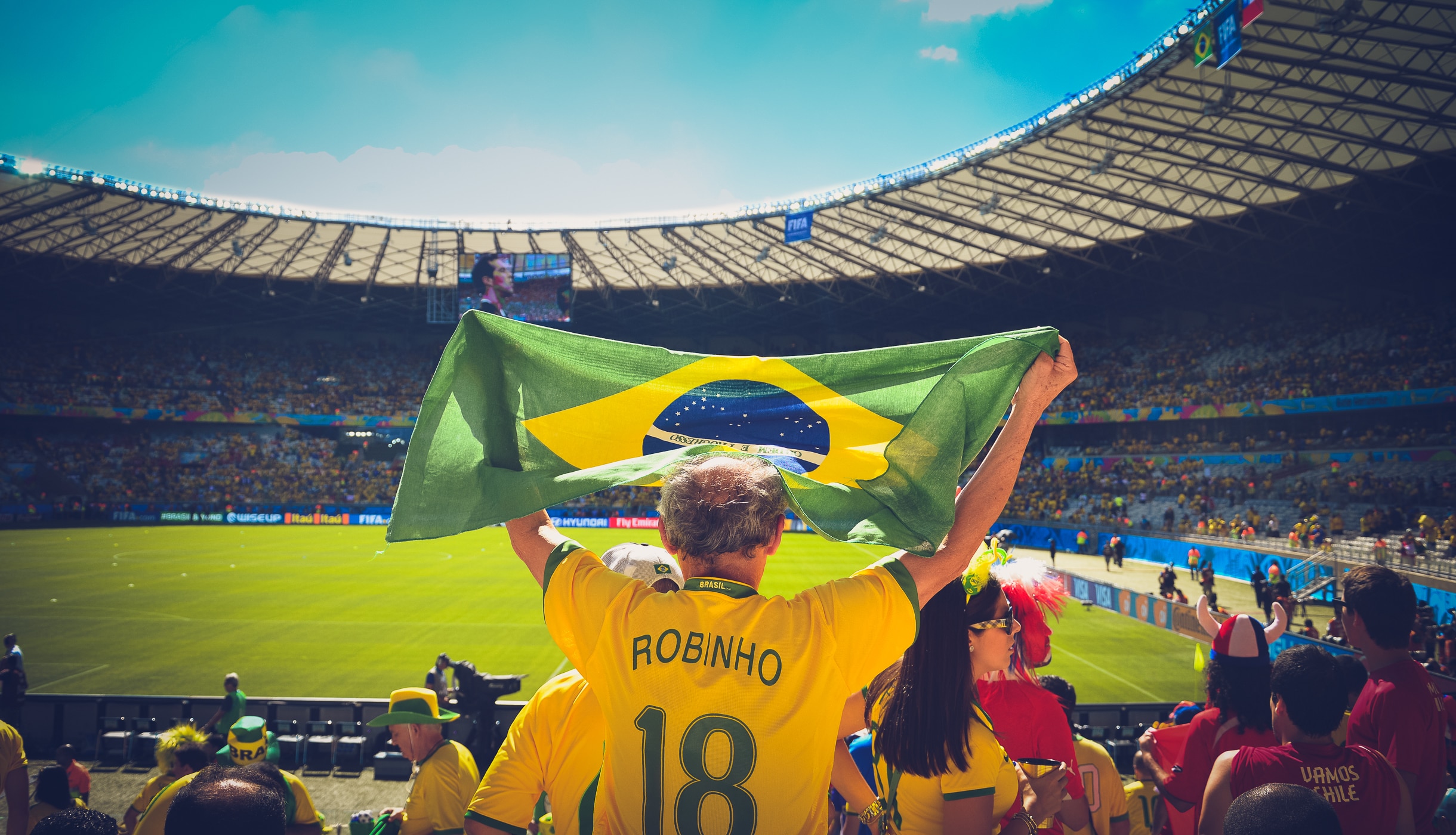 man wearing yellow robinho 18 jersey shirt holding up banner on football stadium
