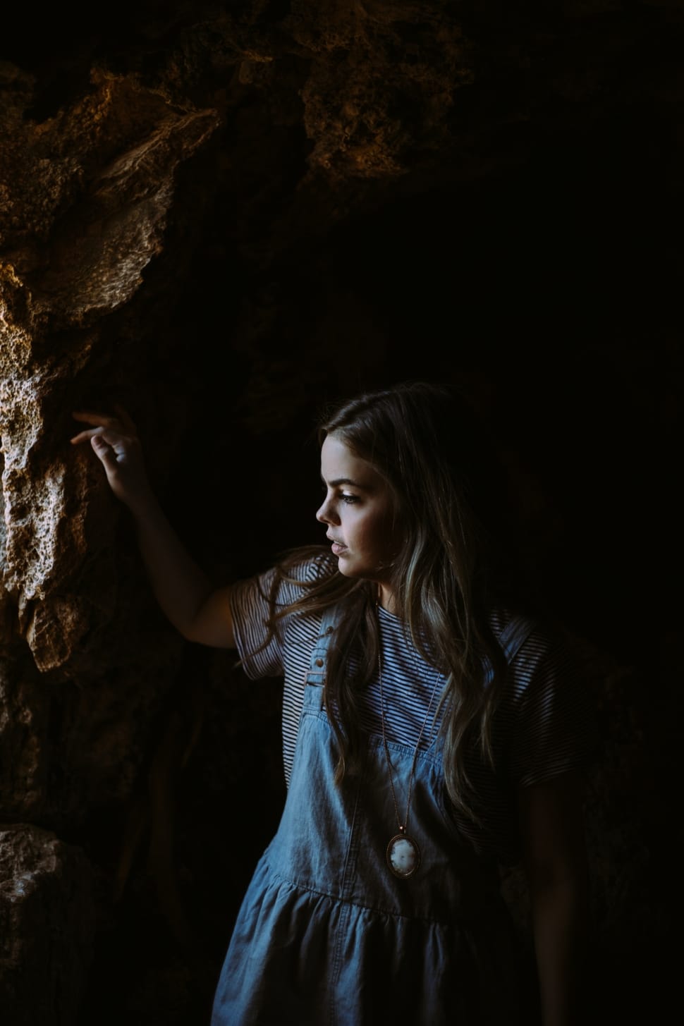 woman on blue dress wearing cameo pendant inside of the cave preview