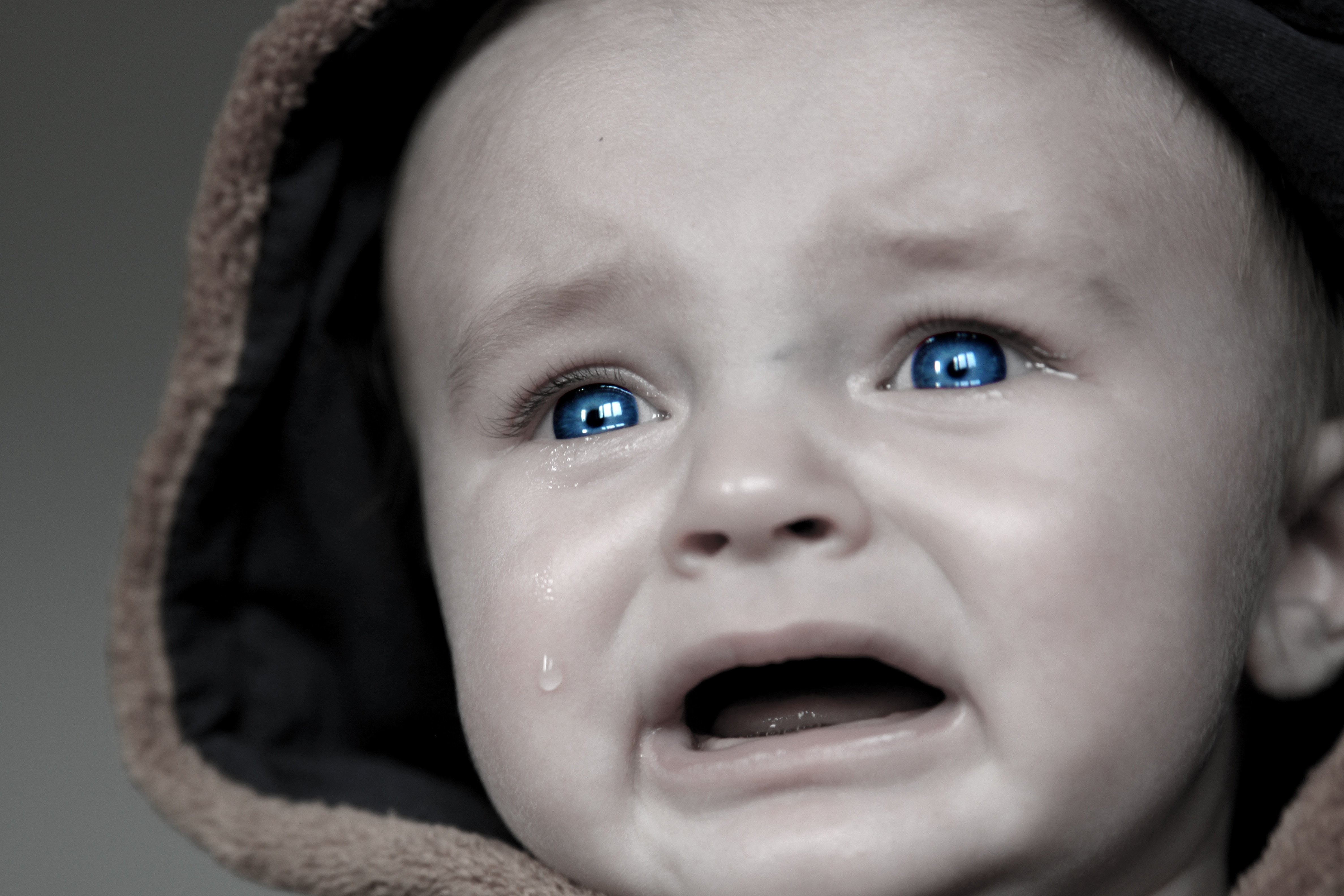 grayscale photography of crying baby in hoodie