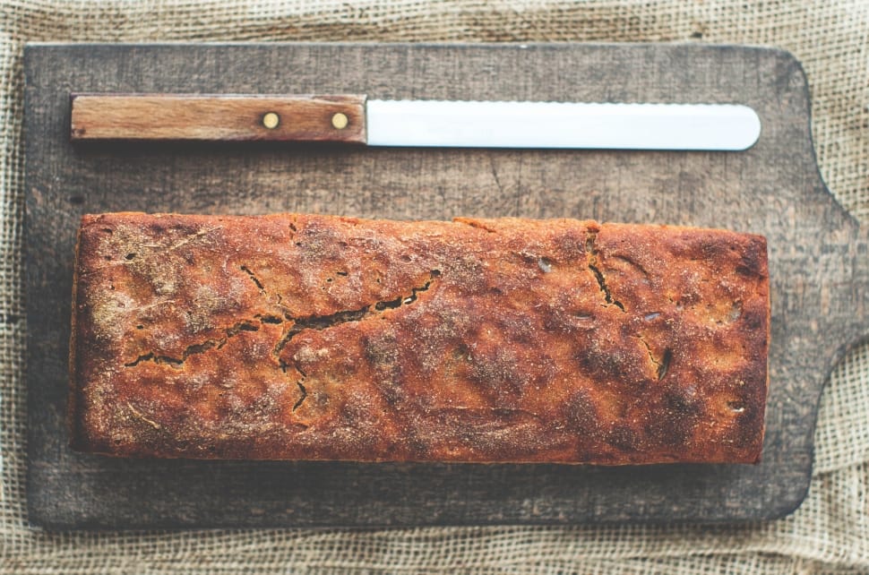 baked bread beside bread knife on black wooden tray preview