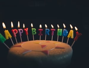 round cake with lighted happy birthday candles thumbnail