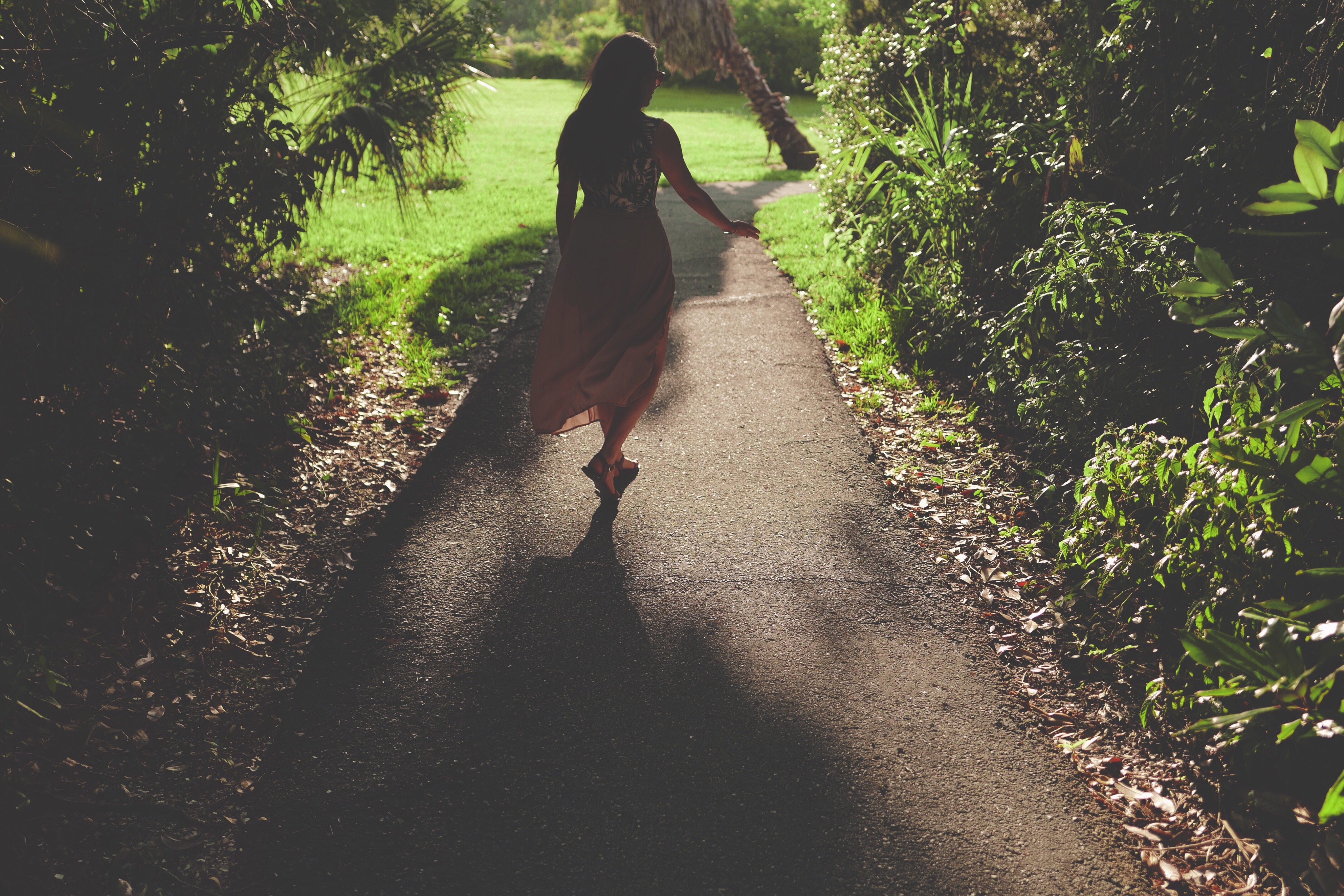 woman in long dress along concrete pathway during daytime
