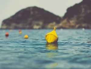 yellow metal bells floating on sea near island thumbnail