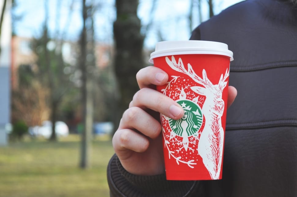 person holding red and white starbucks disposable cup preview
