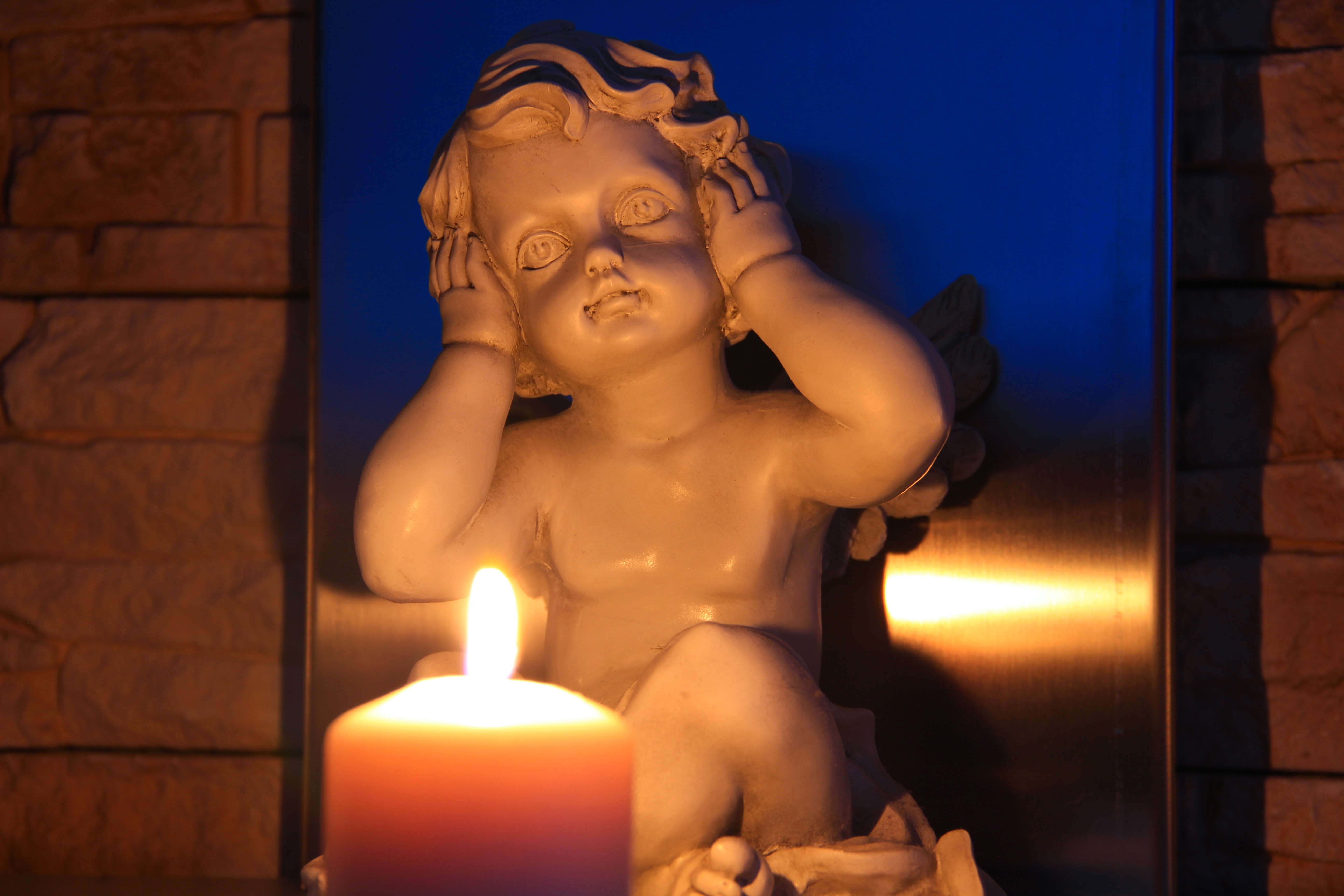 white ceramic cherubim figurine and pillar candle