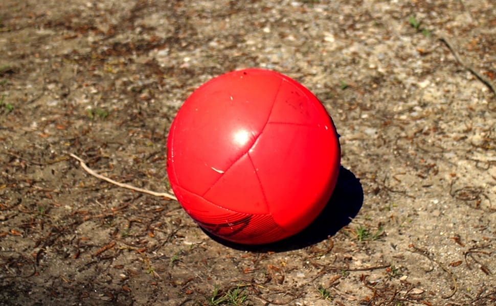 red soccer ball on brown sand preview