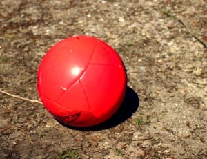 red soccer ball on brown sand thumbnail