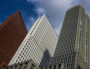 low angle photo of 3 red, white and gray high rise buildings during daytime thumbnail
