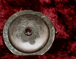 round silver covered container on red fleece textile thumbnail