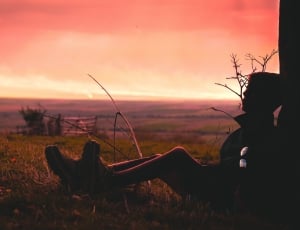 Silhouette of a Man Sitting on the Grass during Golden Hour thumbnail