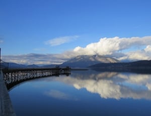 high mountain covered by clouds facing body of water during daytime thumbnail