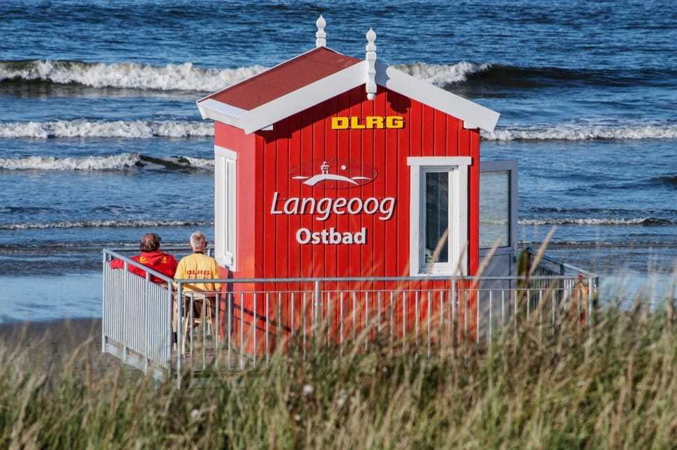 two person standing next to red wall paint DLRG Langeoog Ostbad shed preview