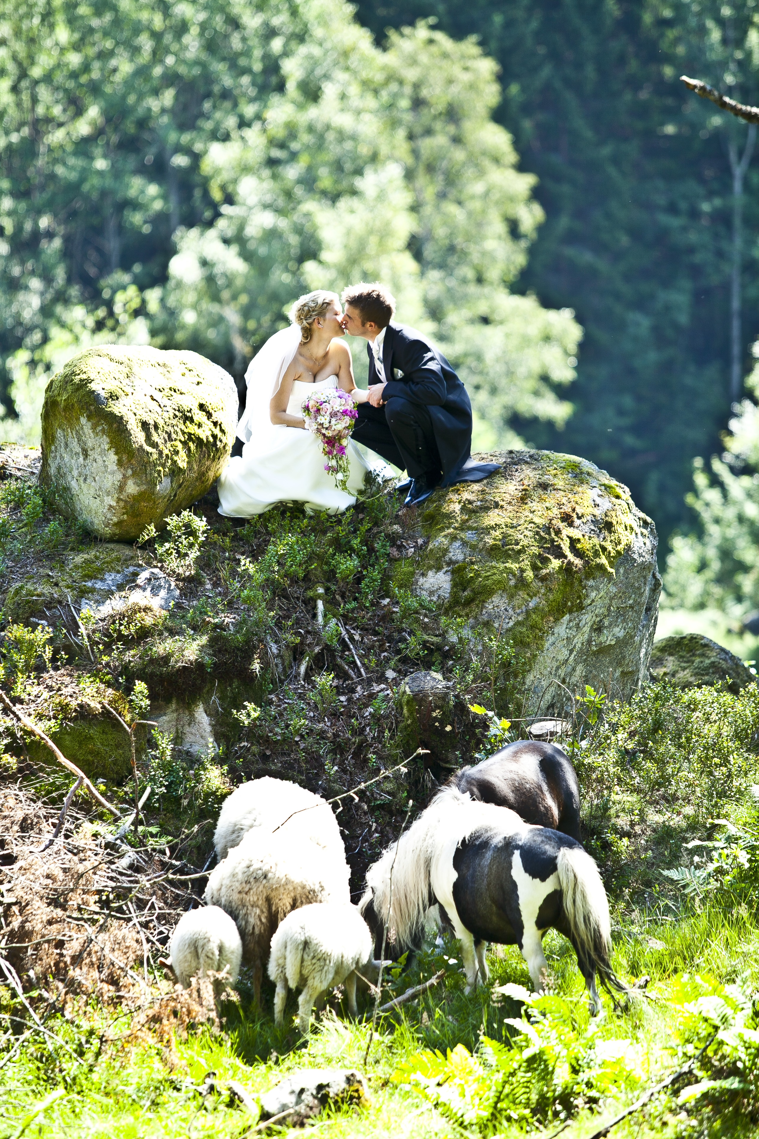 newly wed couple kissing above stones