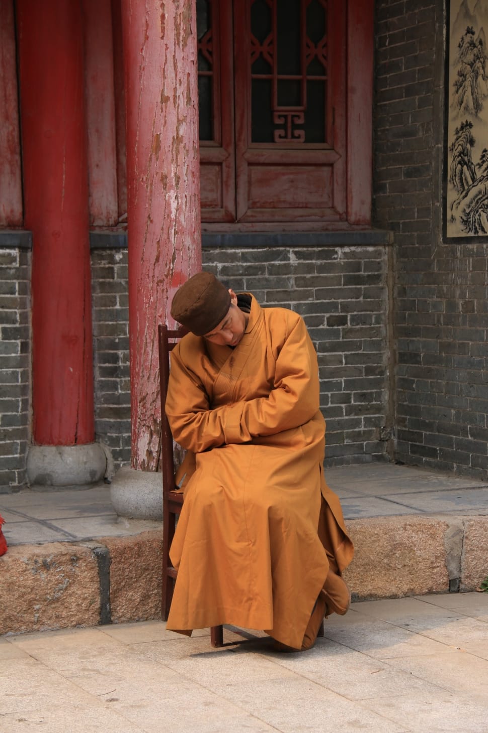 monk sitting on chair near post during daytime preview