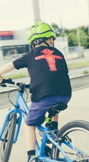 boy wearing black t shirt and blue shorts riding blue bicycle at daytime thumbnail