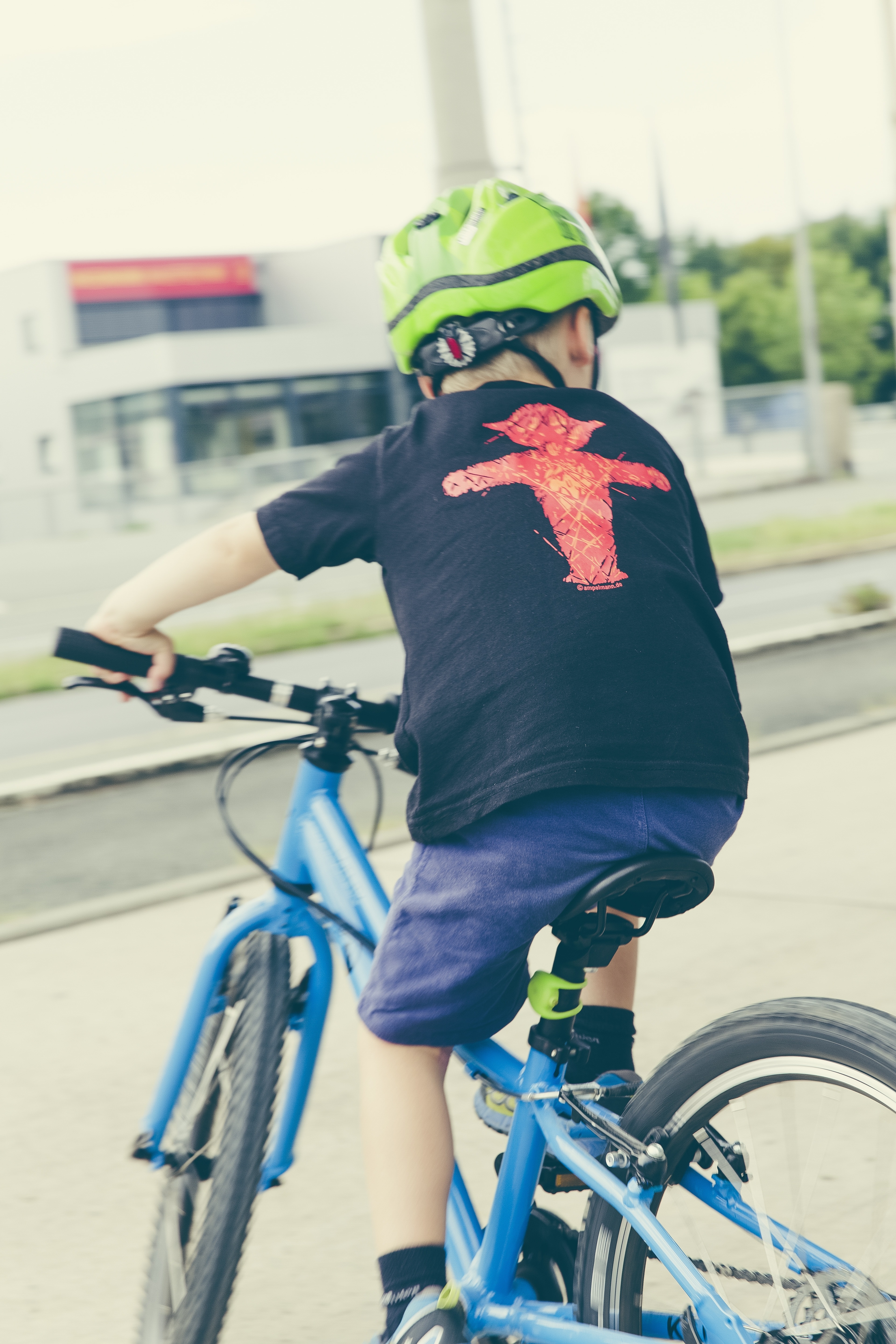 boy wearing black t shirt and blue shorts riding blue bicycle at daytime