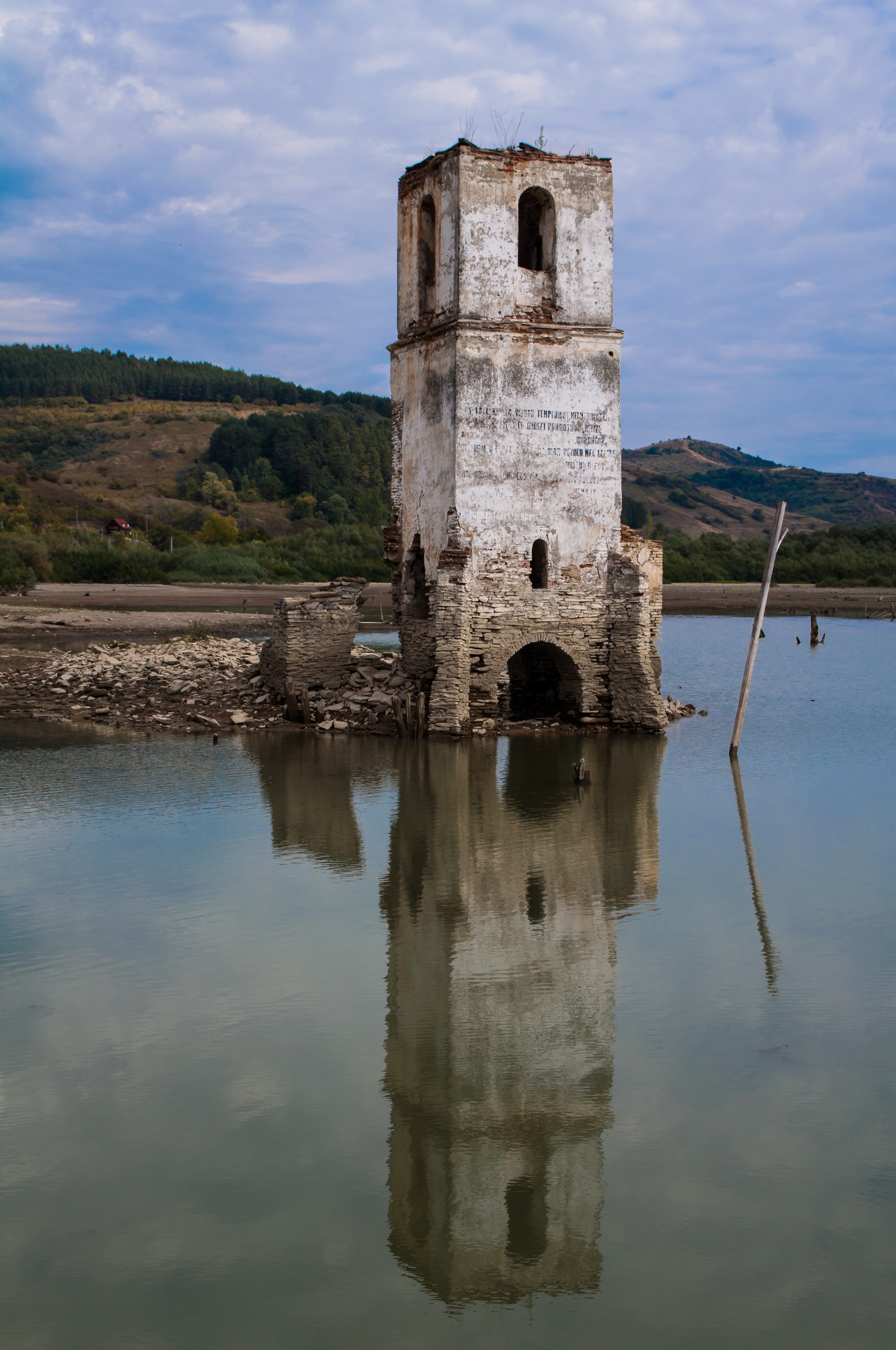 grey and white stone tower beside body of water