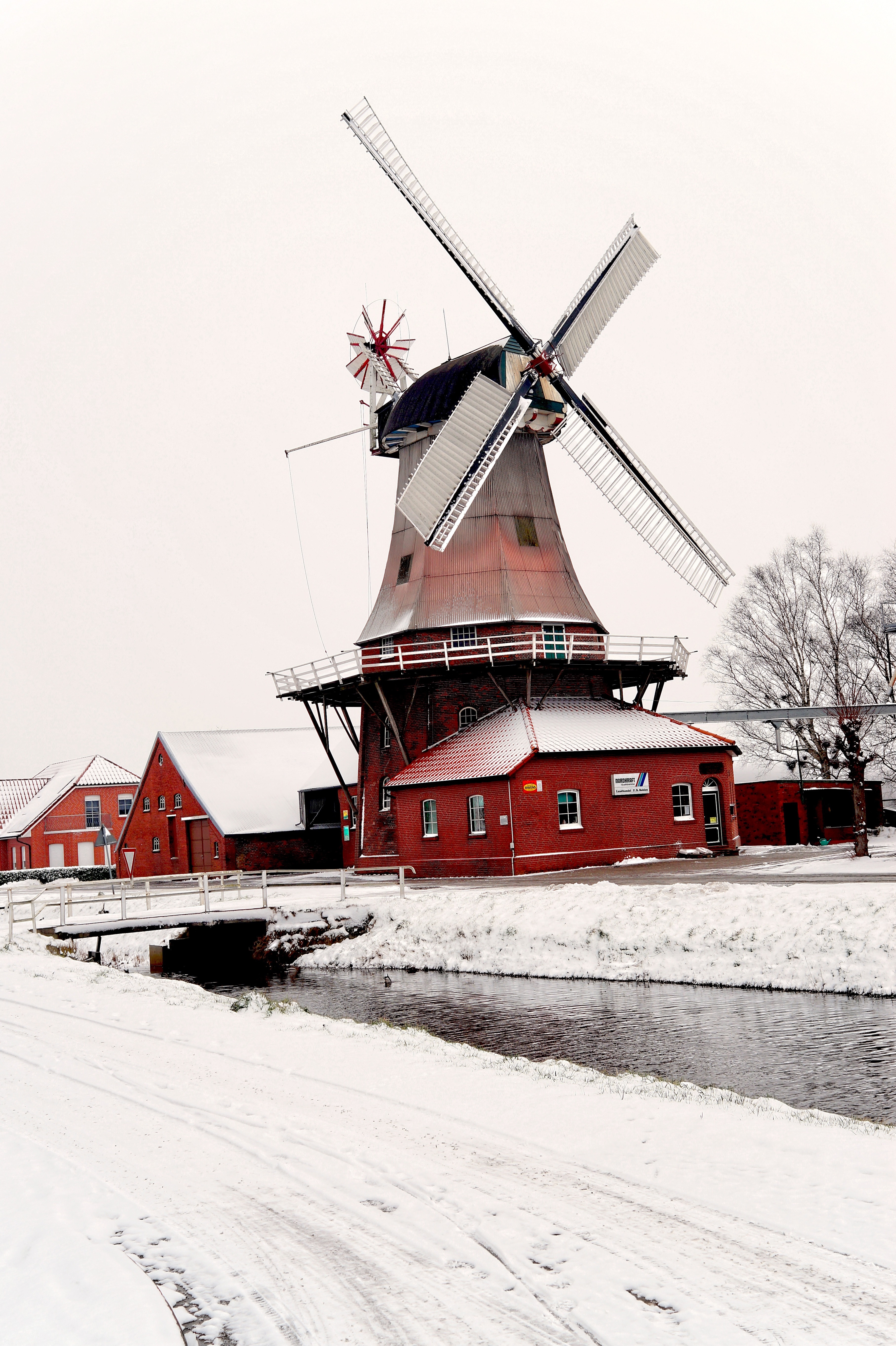 red and gray windmill near bridge during winter