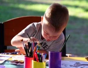 child looking down at the table while holding the crayon pencil thumbnail