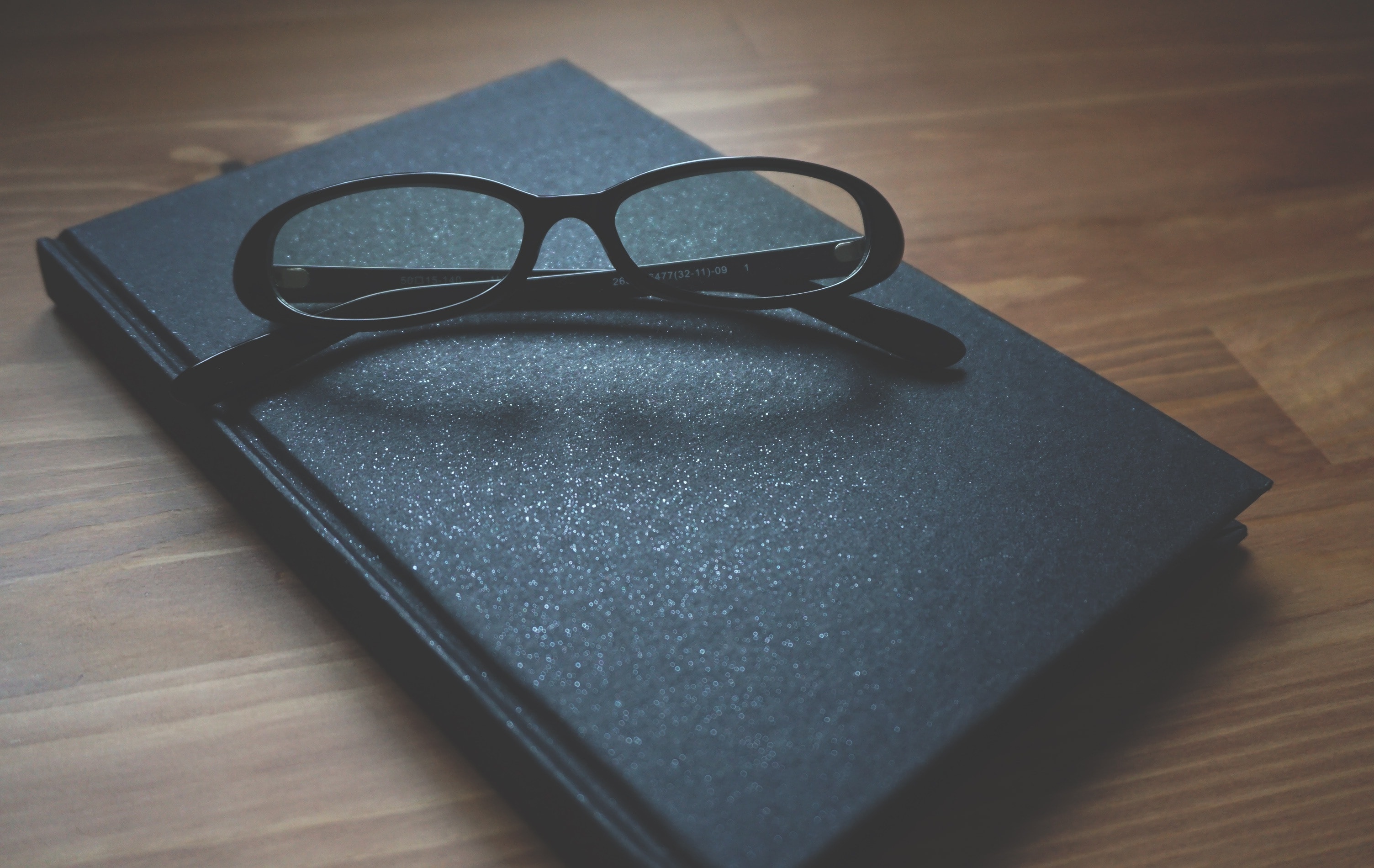 black framed eyeglasses and book