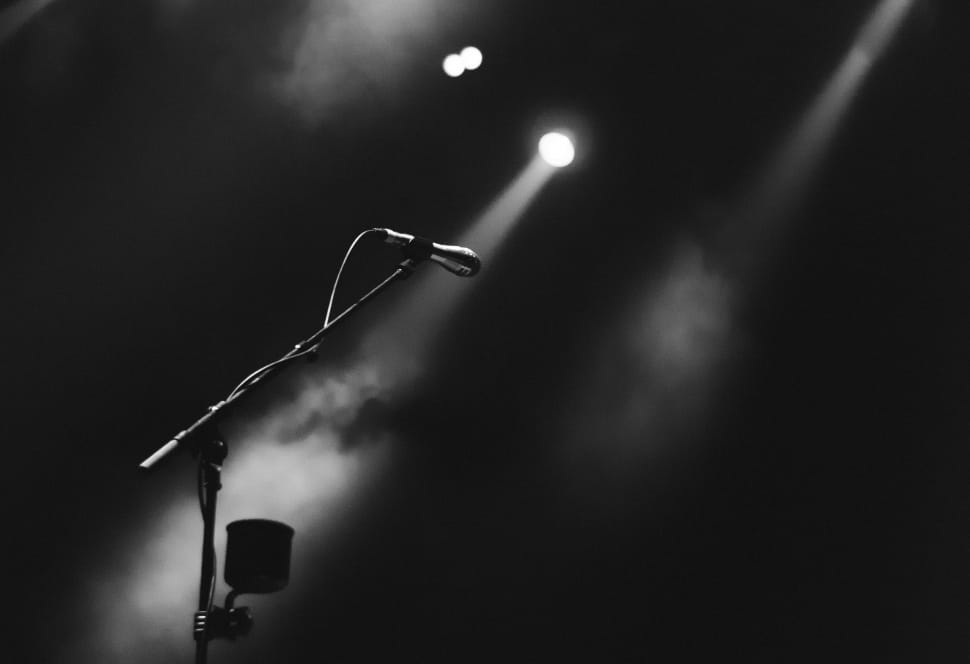 greyscale photo of a microphone on stand with spotlight preview