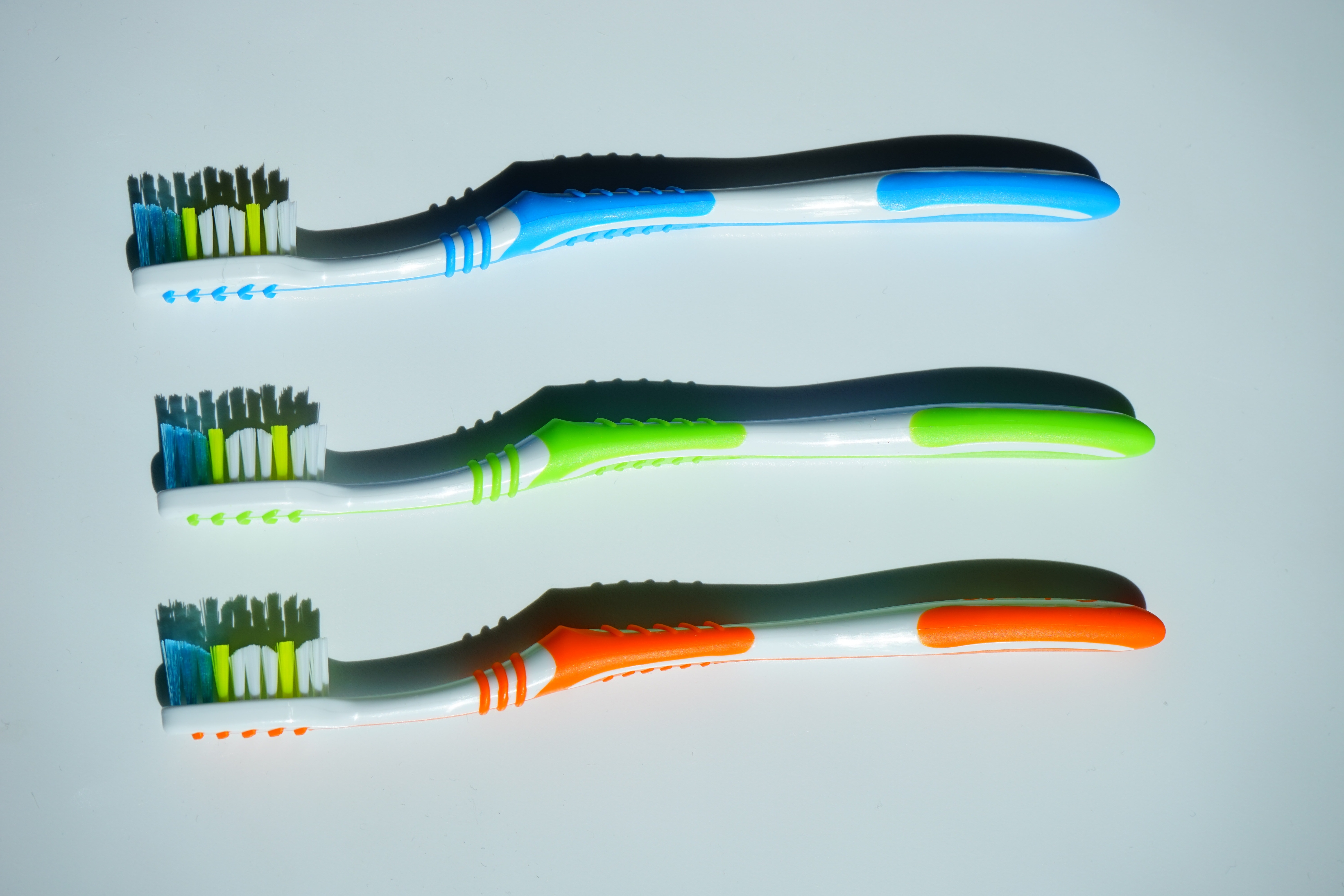 three blue, green, and orange tooth brush on white surface