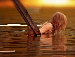 woman half dip on body of water near brown wooden handle thumbnail