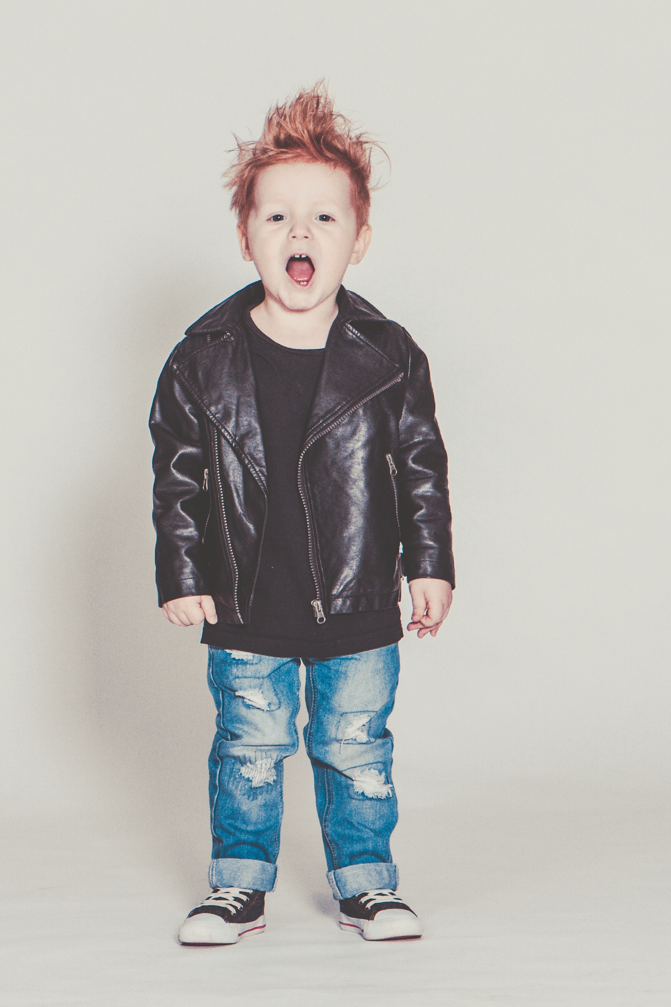 boy's black leather jacket, blue distressed jeans, and lace up low tops outfit