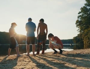 4 men standing on sand near lake thumbnail