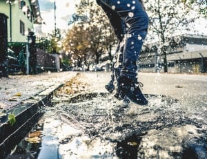 person jumping on puddle during daytime thumbnail