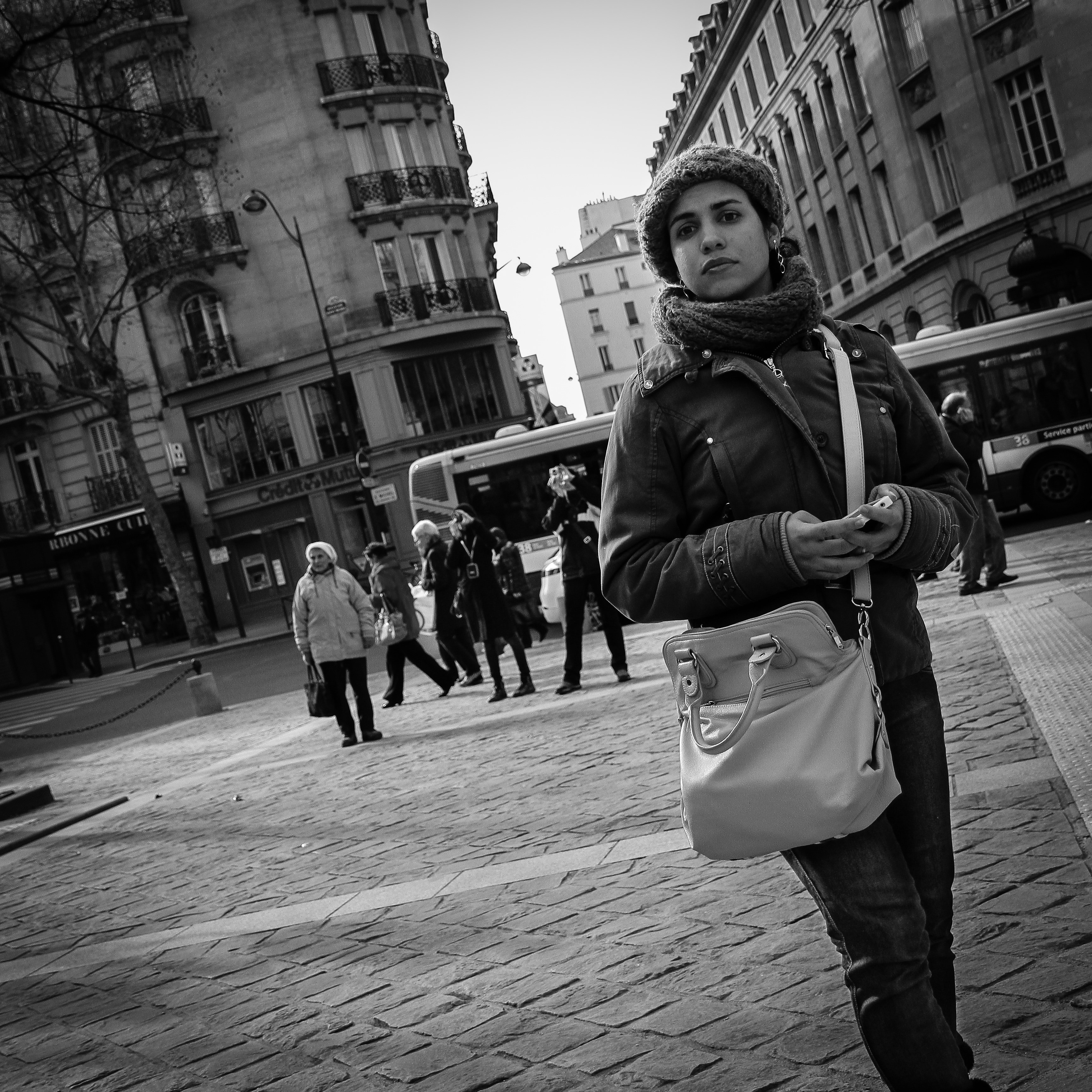 gray scale photo of woman walking beside buildings