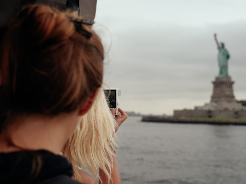 woman taking a picture of liberty statue preview