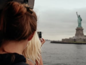 woman taking a picture of liberty statue thumbnail