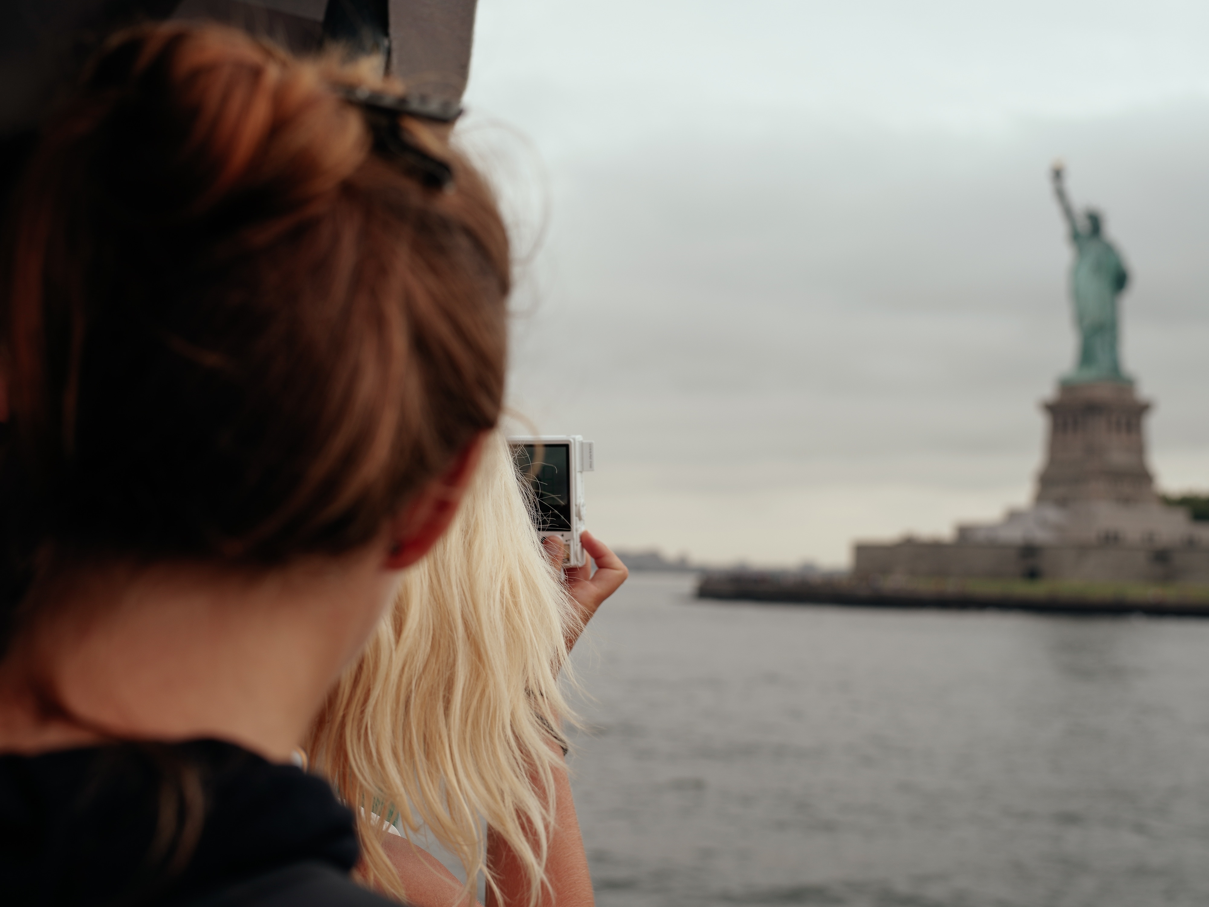 woman taking a picture of liberty statue