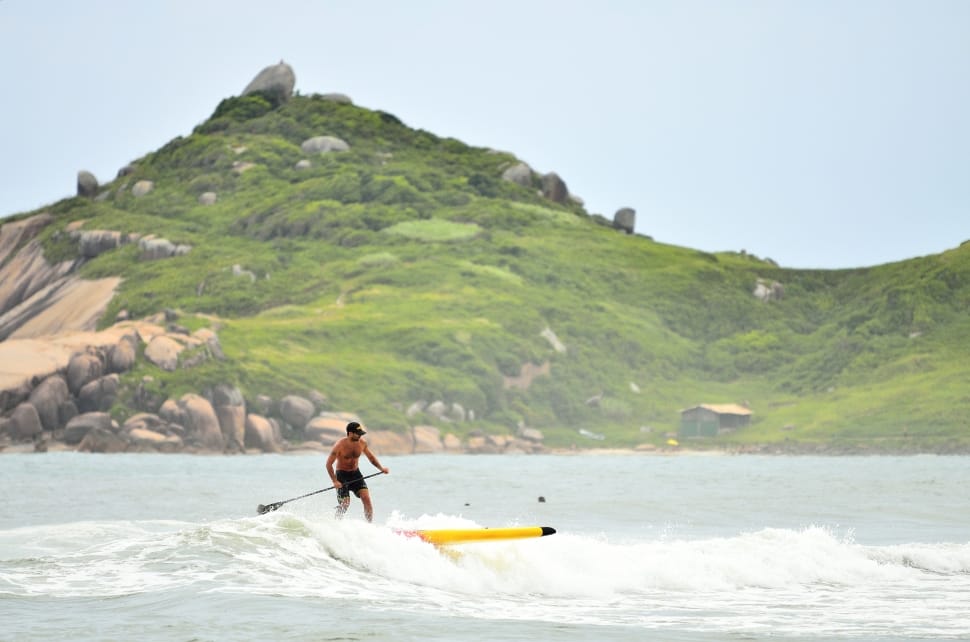 man in black shorts riding yellow surfboard during daytime photo preview