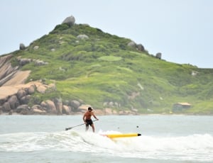 man in black shorts riding yellow surfboard during daytime photo thumbnail