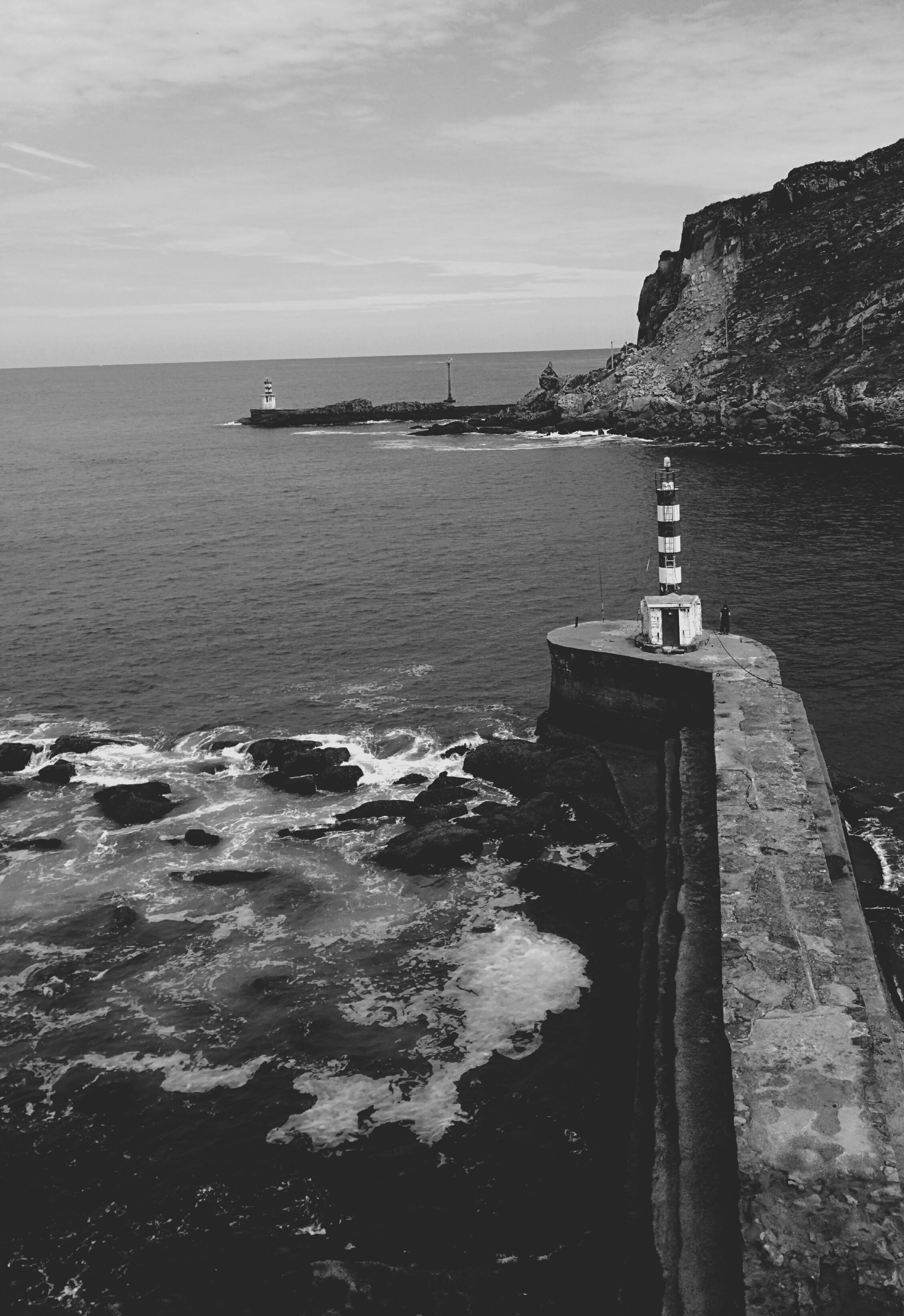 greyscale photo of lighthouses and wavy sea