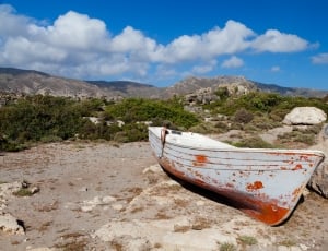 white and red canoe beside brown rock during daytime thumbnail
