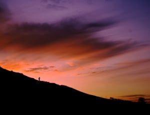 silhouette of person climbing down a hill during golden hour thumbnail