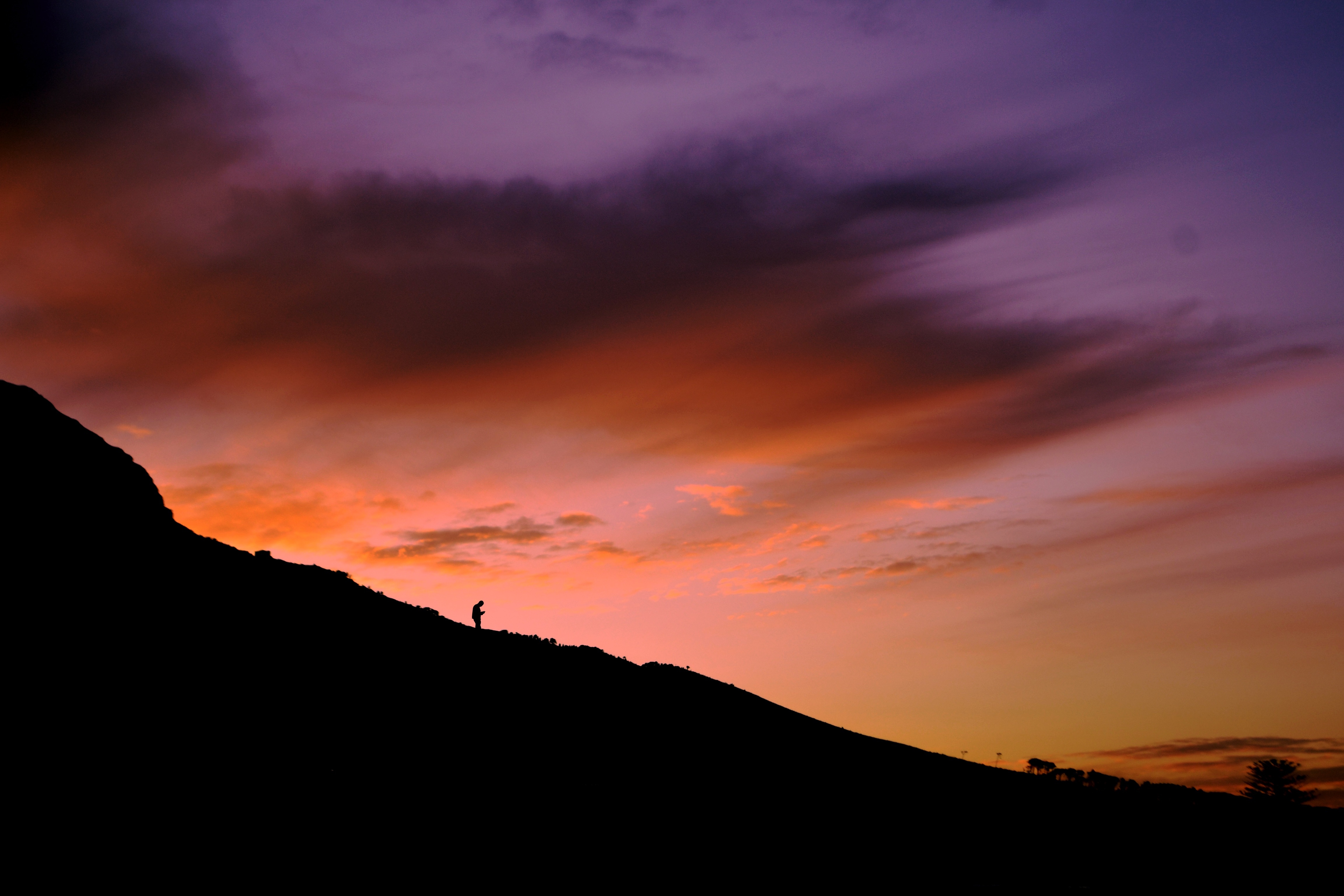 silhouette of person climbing down a hill during golden hour