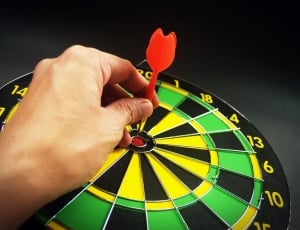 black,white and green dartboard with red dartboard sticking on it thumbnail