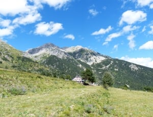 house in front of mountain surrounded by trees under clear sky thumbnail
