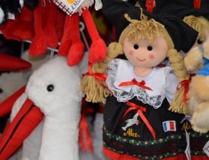 close up photo of white and red duck plush toy and rag doll in black dress thumbnail