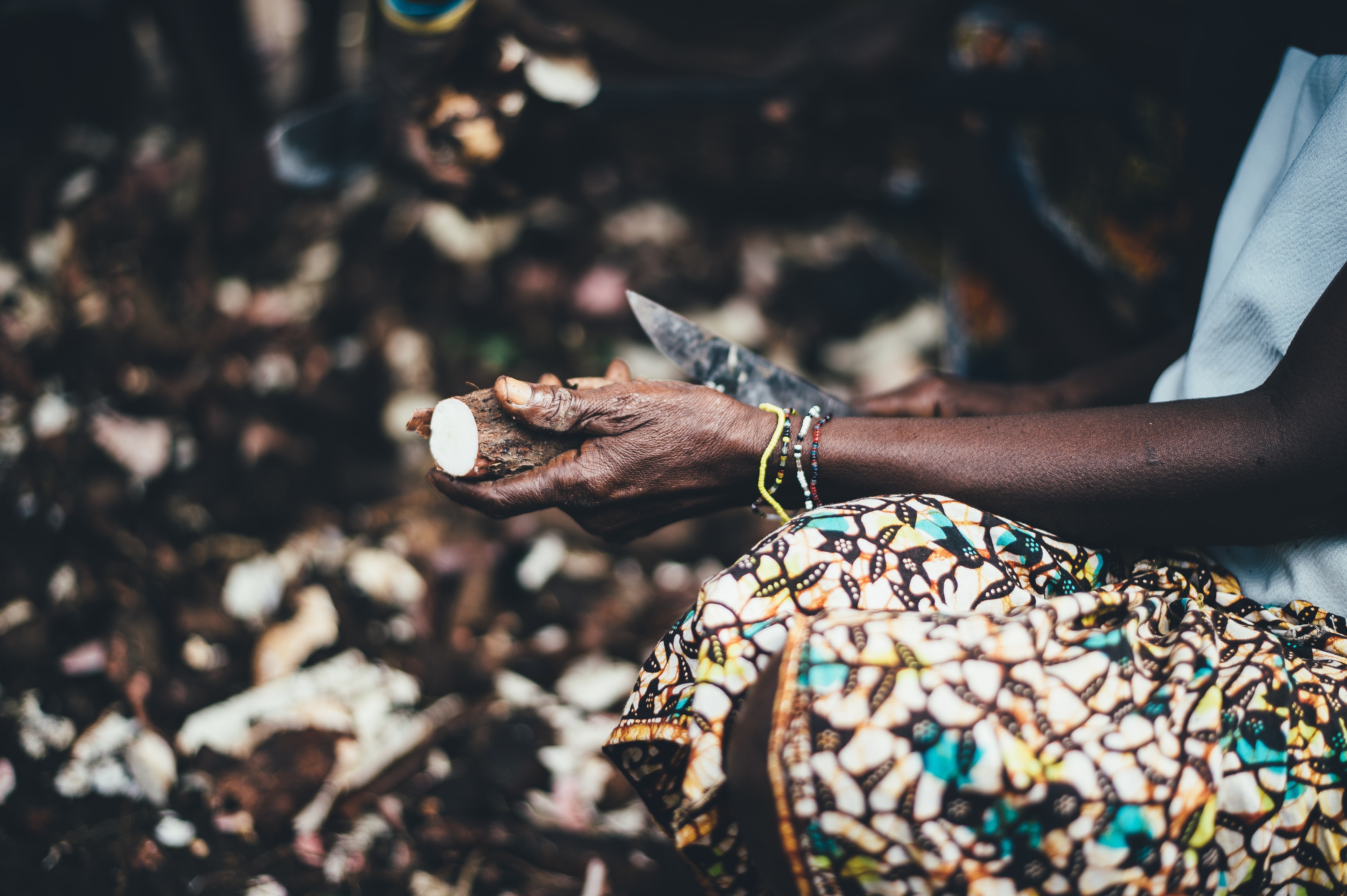 person holding knife and cassava