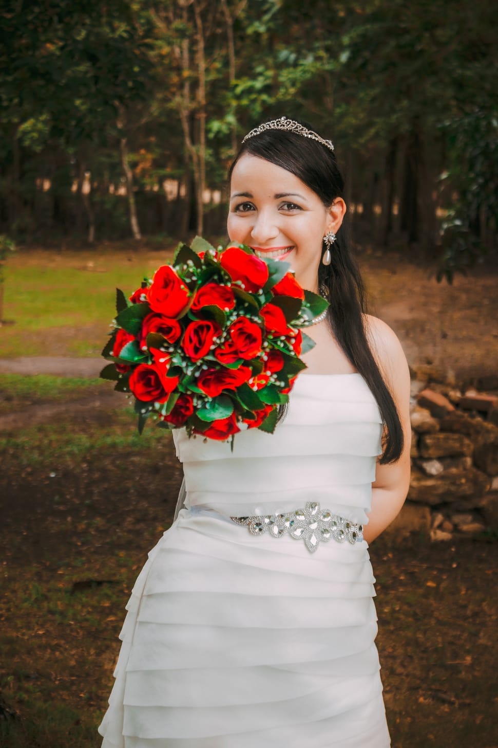 woman wearing wedding gown holding red rose bouquet preview